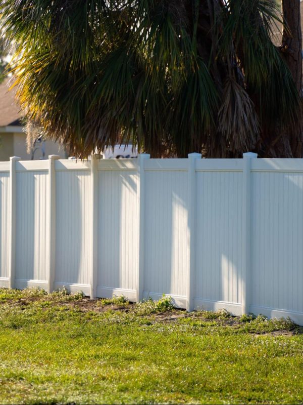 Vinyl fencing next to a home and trees.