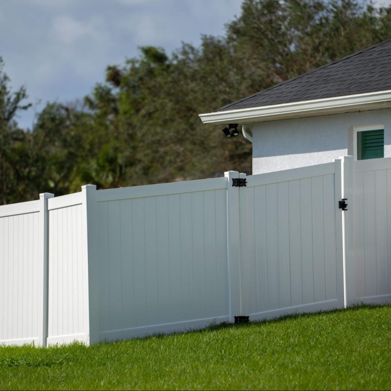 Vinyl fence with a gate next to a home.