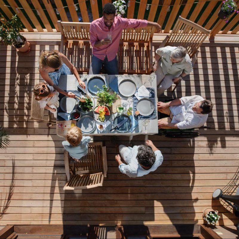 An aerial view of friends eating lunch on a deck.