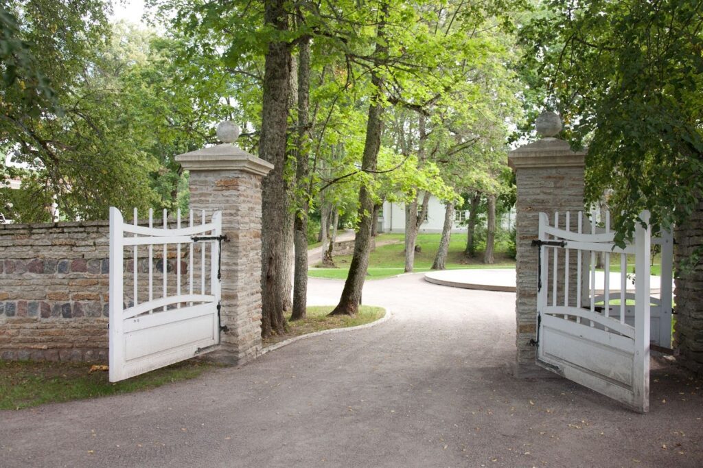 A white gate is opened in front of a home.