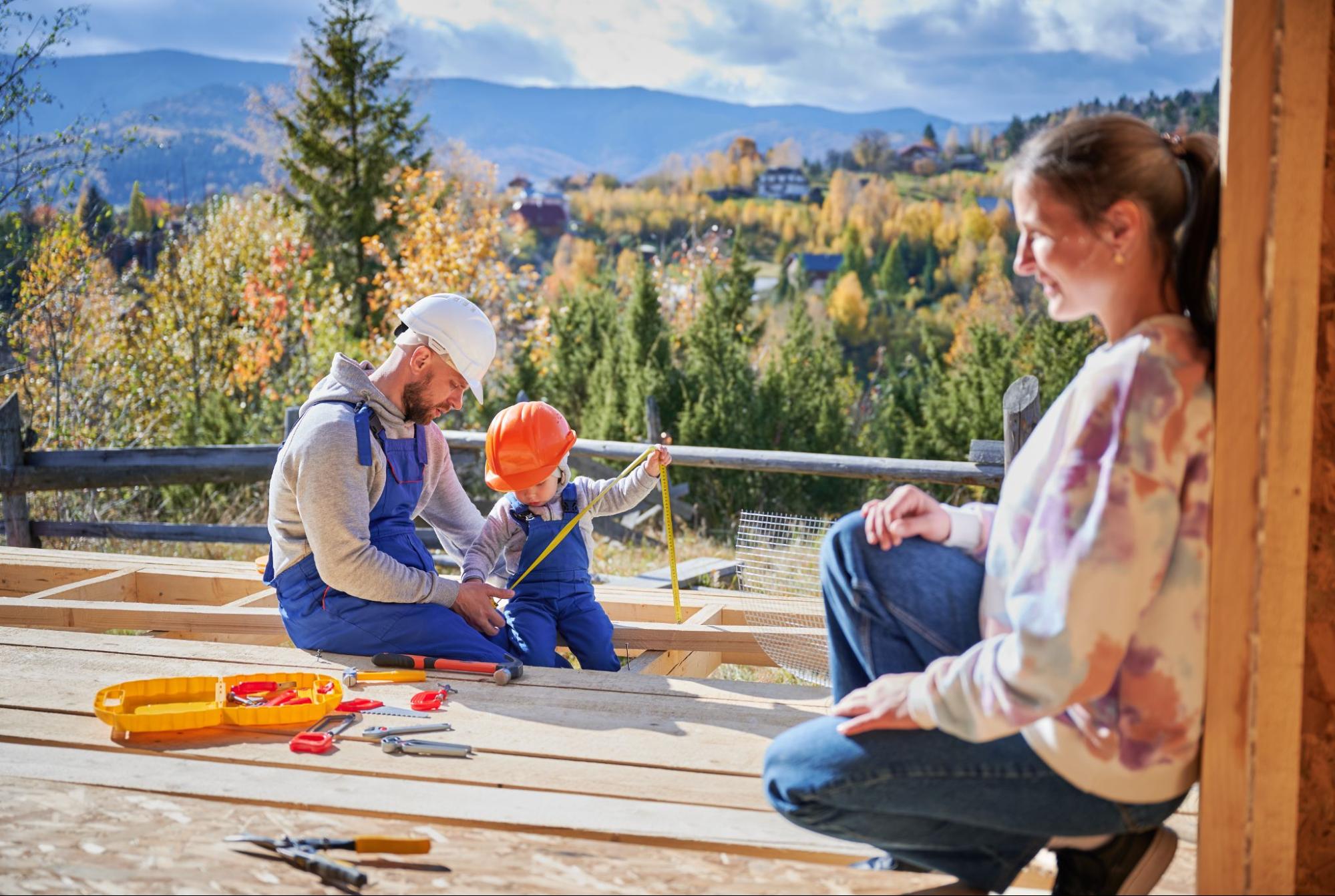 A mother watches her husband and son build a wooden deck frame.