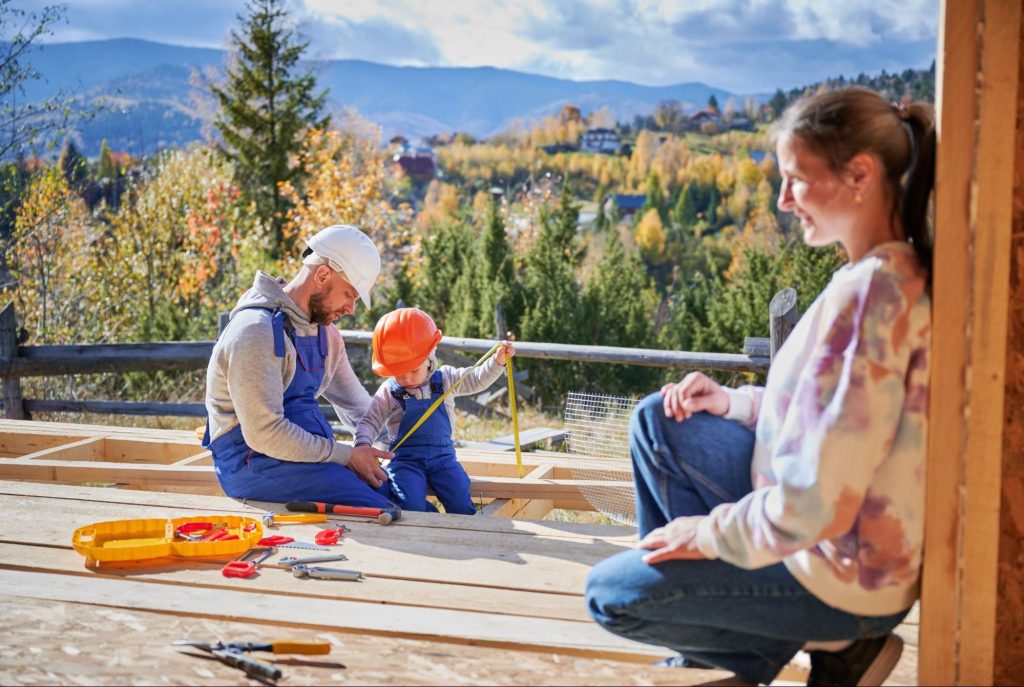 A father explains to his son how to fix their deck while a mom watches them.