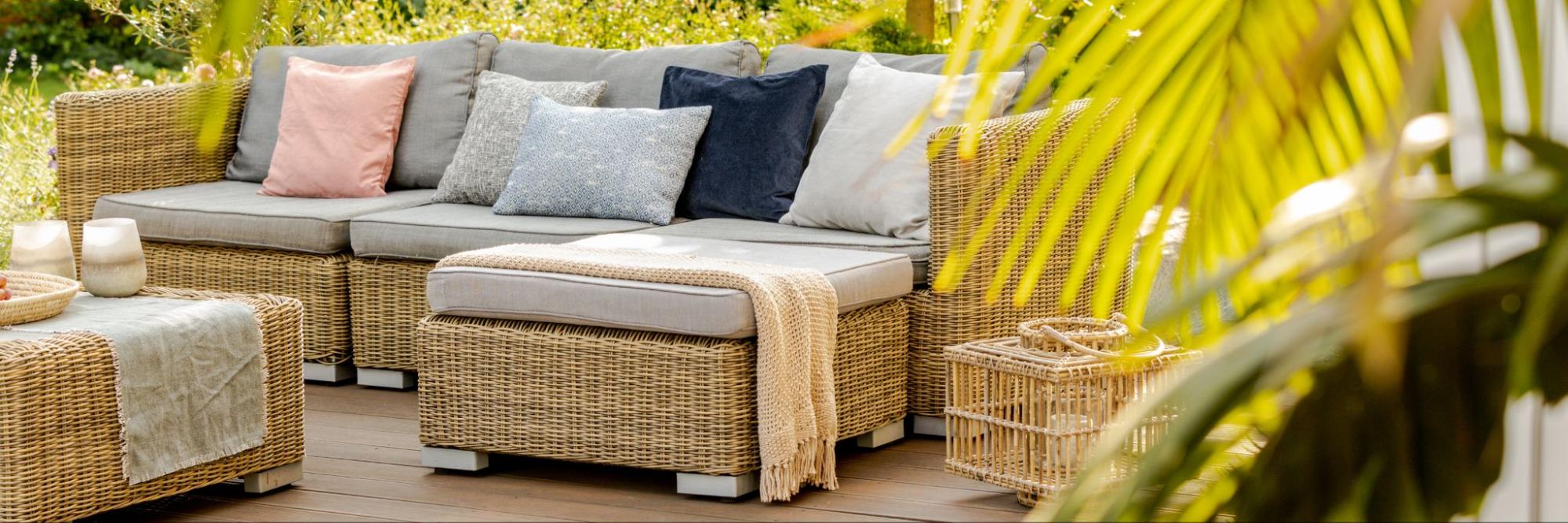 Surrounded by plants, a spacious terrace with cozy rattan furniture and a wooden floor creates a welcoming ambiance.
