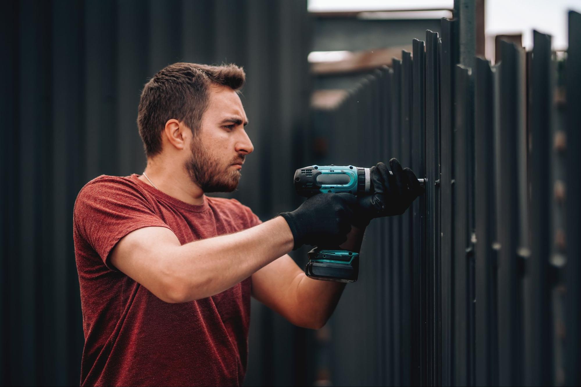 A construction worker is using drilling screws to fasten and drill screws to steel fences.