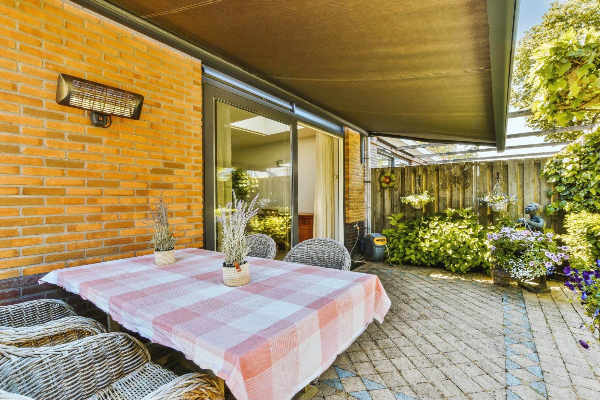A patio with a table and chairs surrounded by plants.