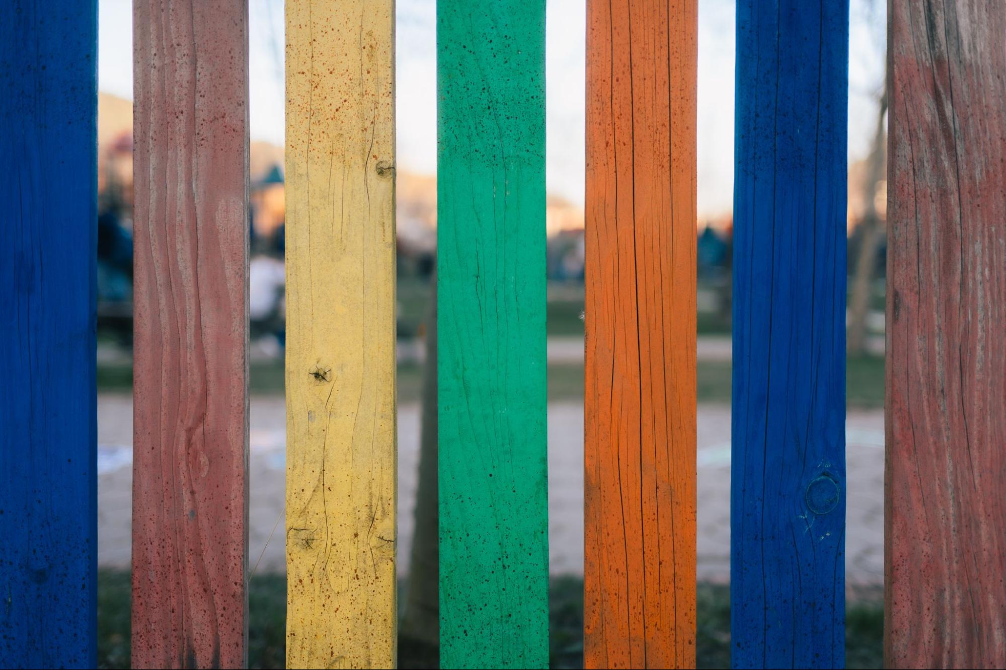 Wood fence planks are painted in different colors.