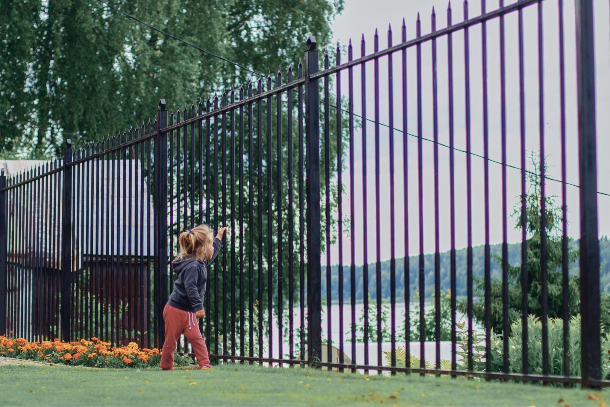 A girl playing in the backyard, surrounded by iron fences.