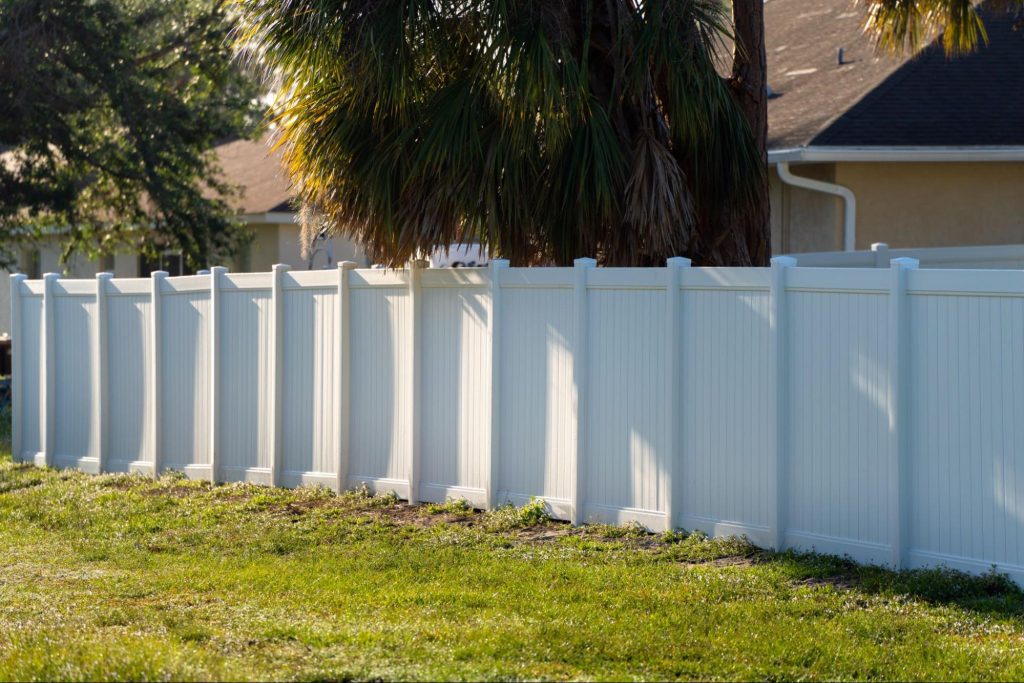 Vinyl fencing next to a home and trees. 