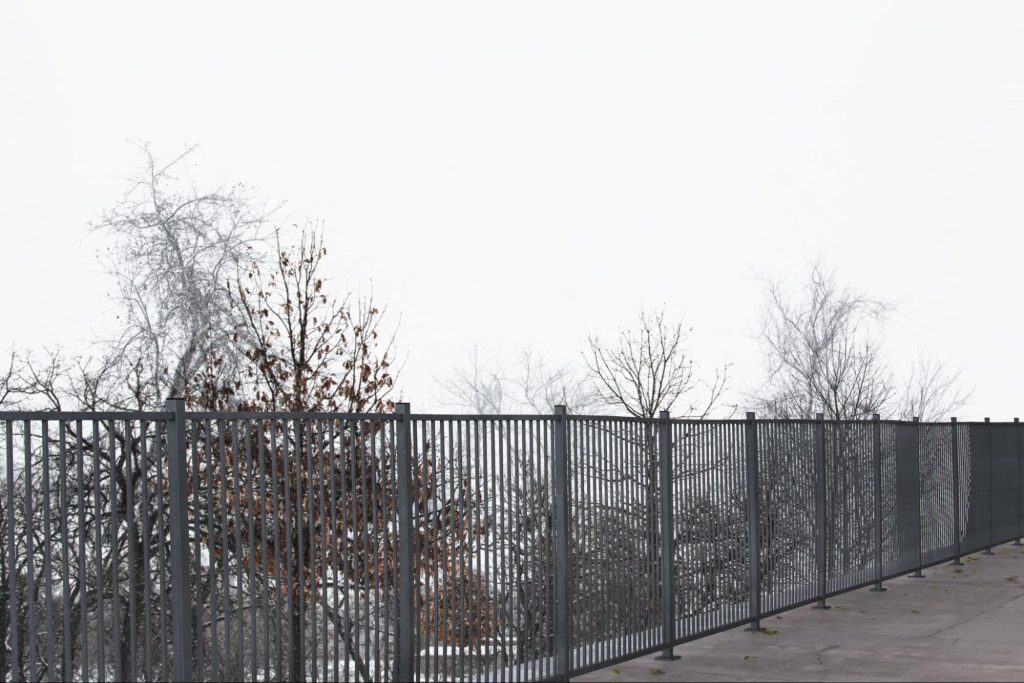 Aluminum fence with trees in the background. 