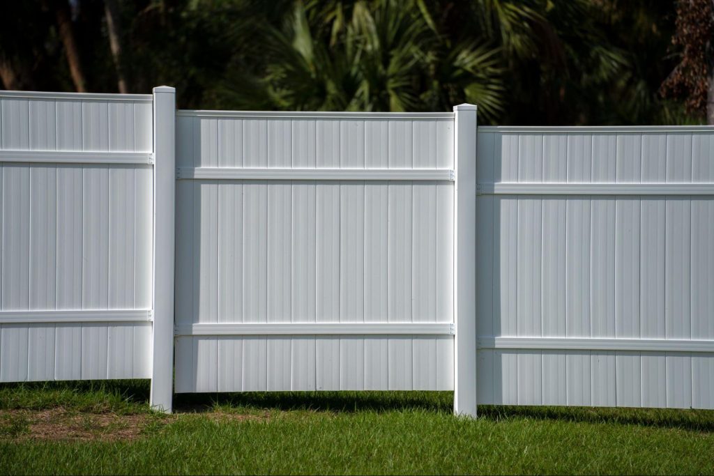 Vinyl fence with trees in the background. 