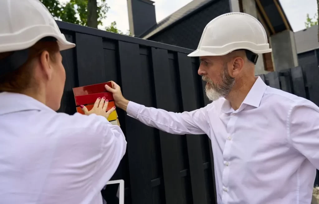 A male customer discusses pre-colored choices to find the perfect match for his vinyl fence with the guidance of a female fence contractor.