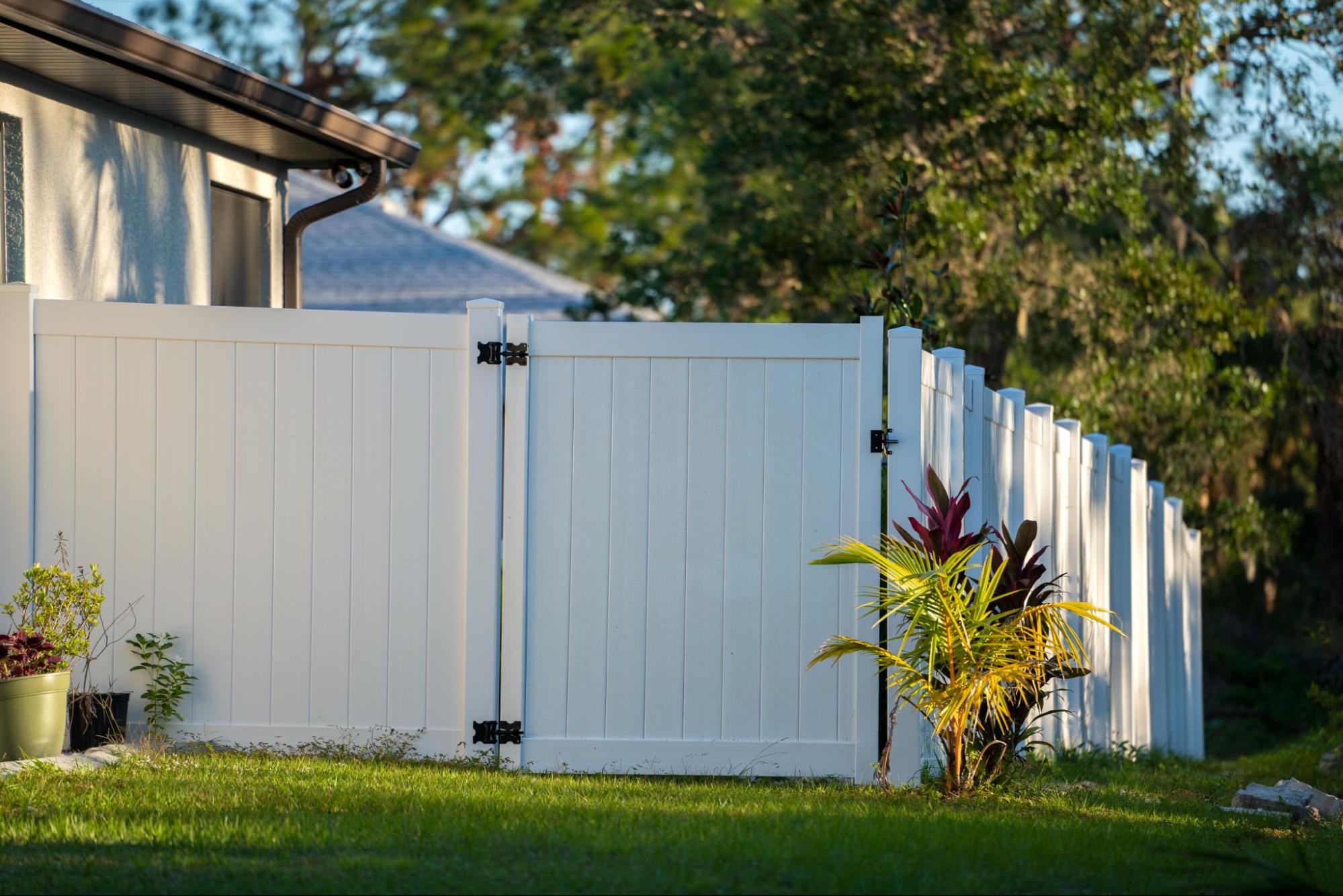 Elegant white vinyl picket fence on a lush green lawn, enclosing the property with well-manicured landscaping in front.