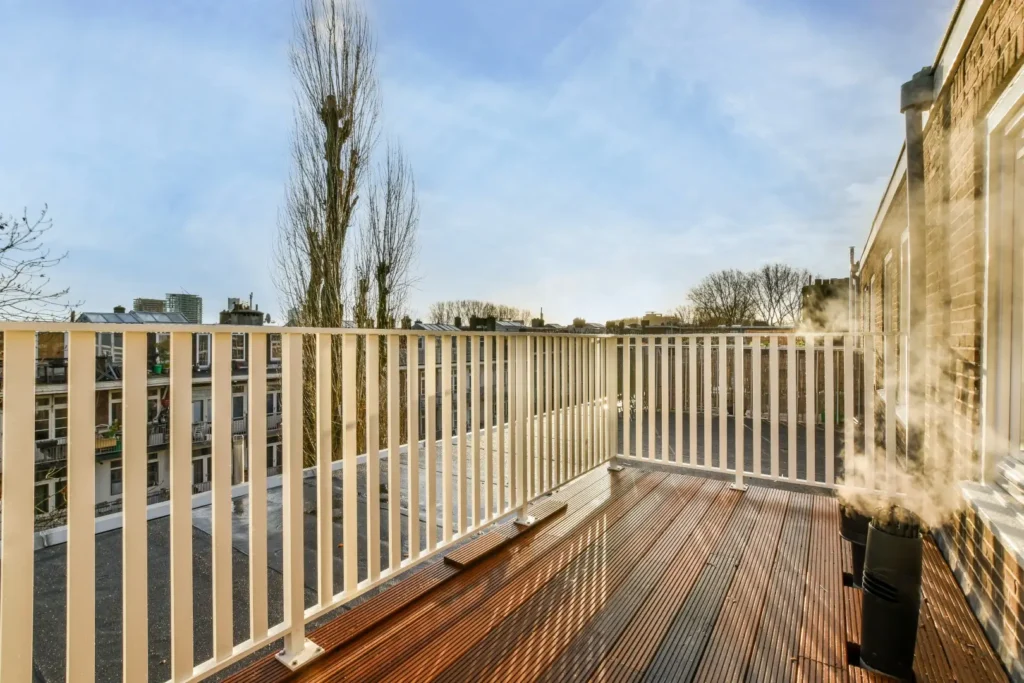 A picture of decking boards of a porch with white railings.