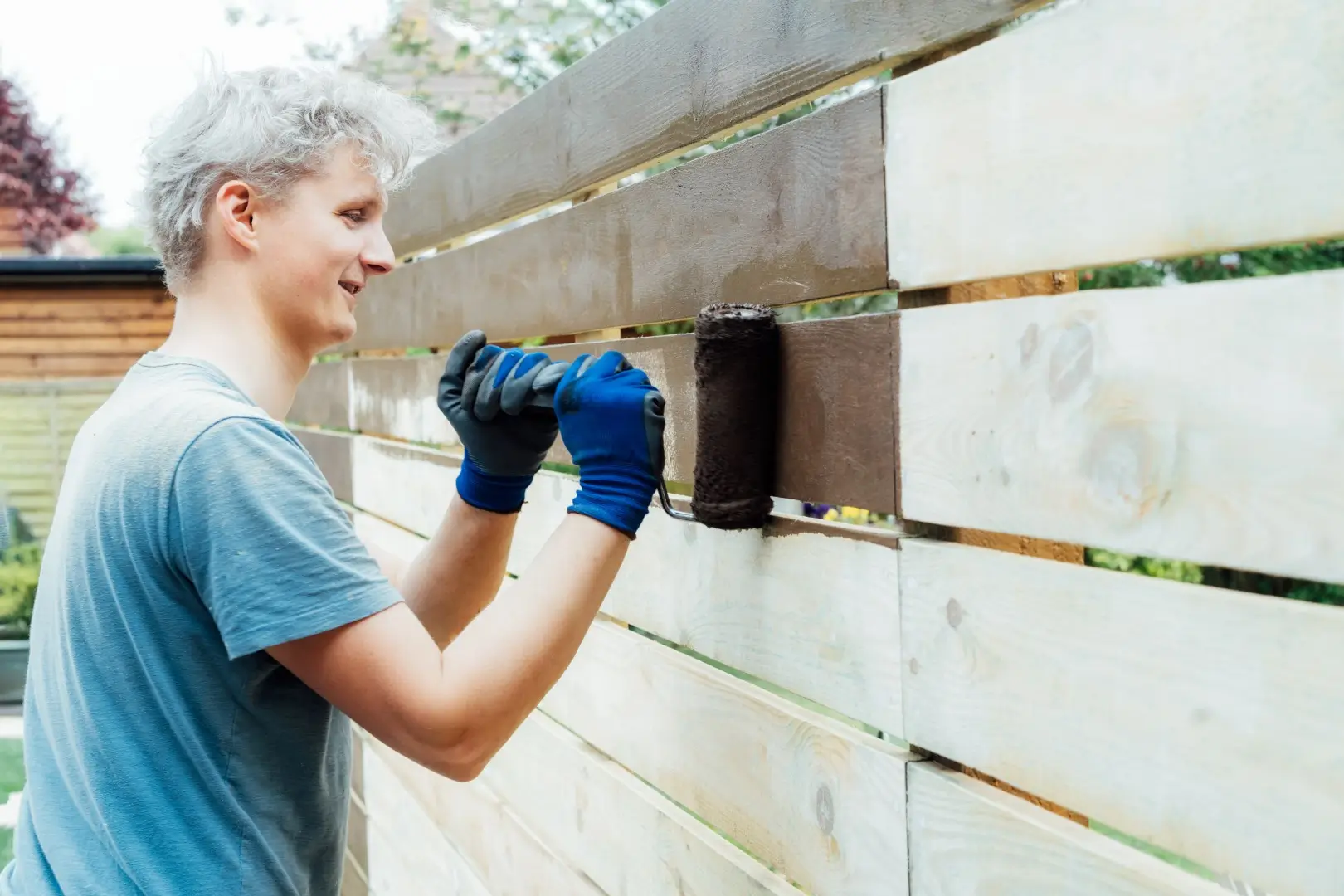 A professional fence installer adds finishing touches to a steel fence with brick posts.