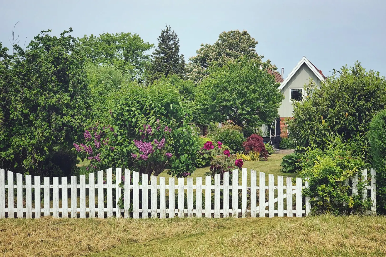 A white vinyl fence surrounds a residential home.