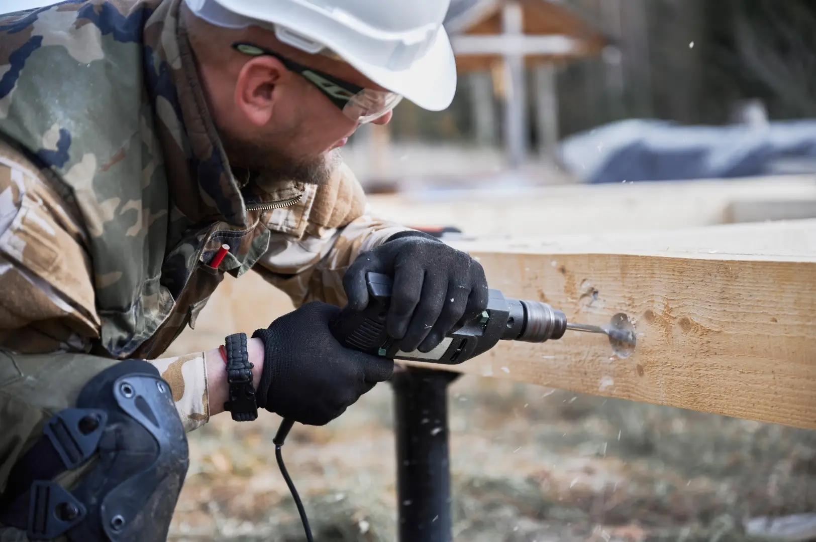 A worker is drilling into a piece of wood for a deck.