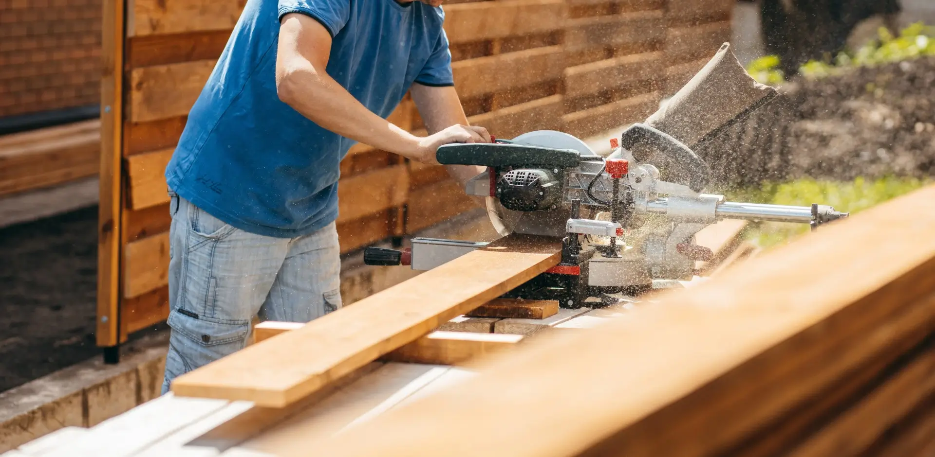 Adult man assembling a modern wooden fence.