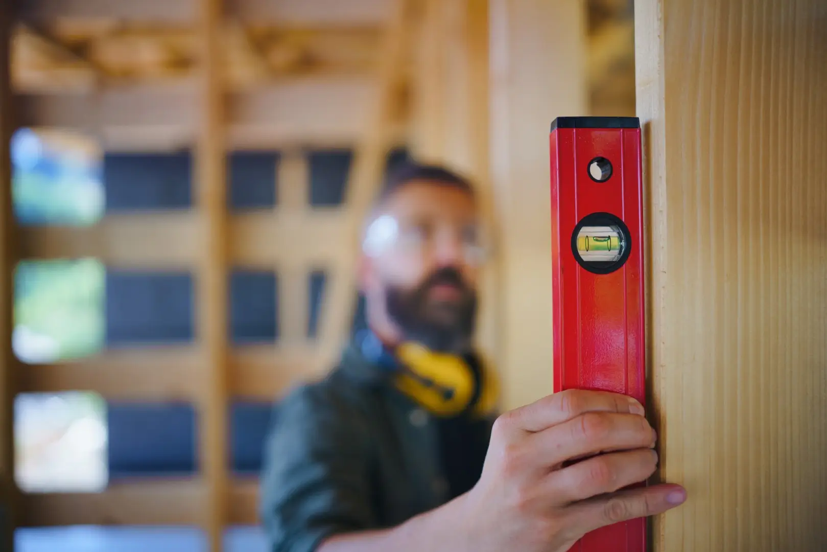 Carpenter checking wooden planks with spirit level.