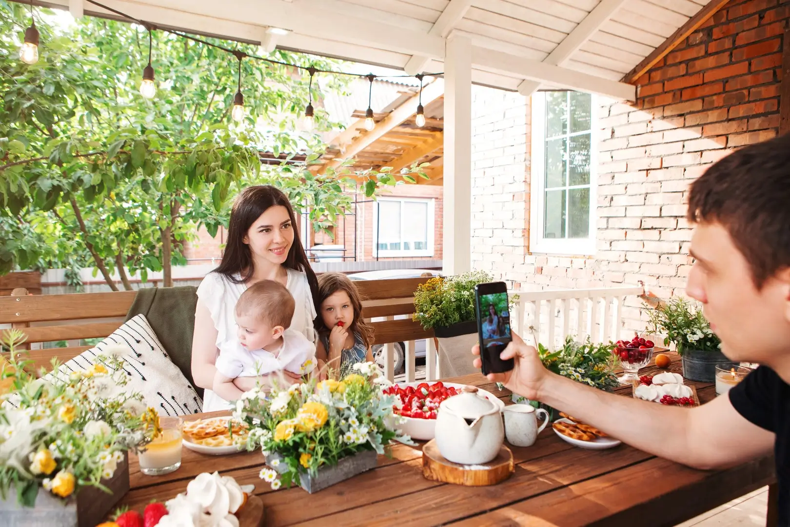 Family sitting under a vinyl patio cover and taking a photo.