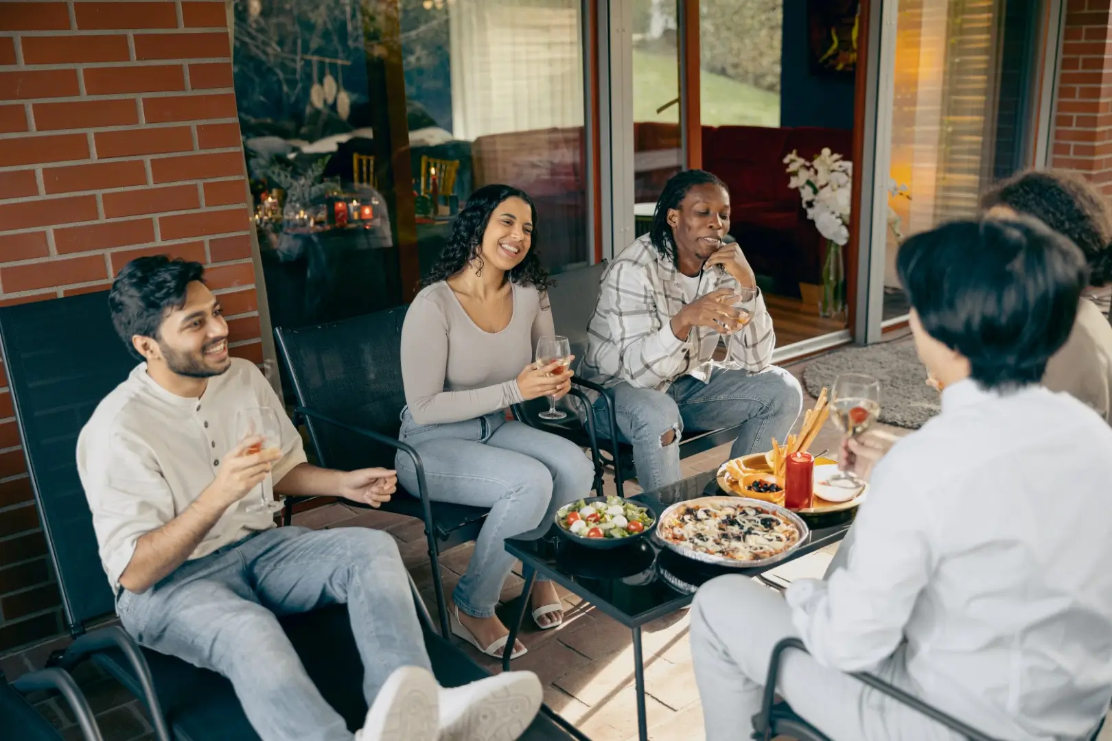 Four friends are enjoying eating pizzas on a porch.