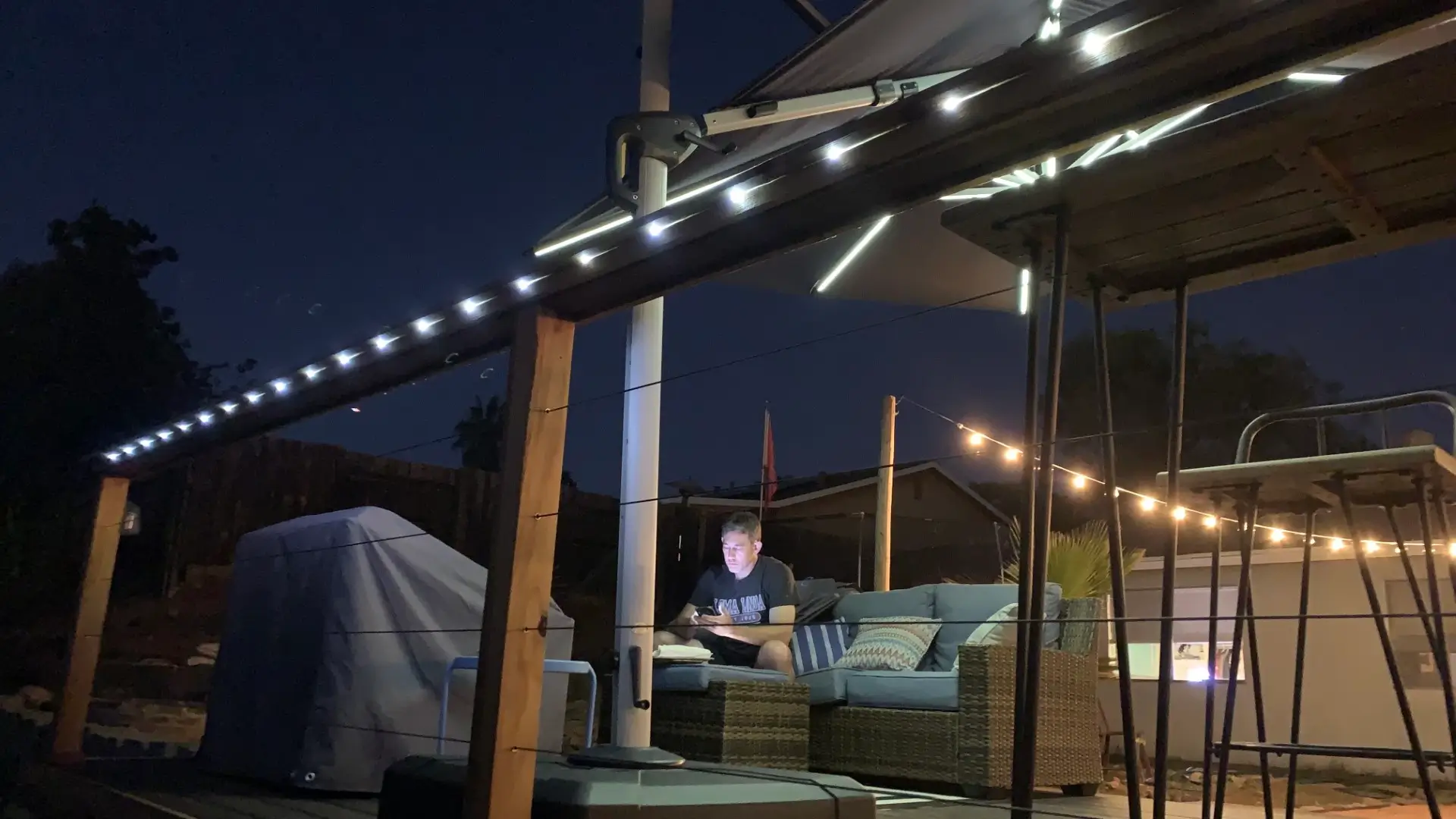 Friends drink wine on a deck illuminated by LED lights.