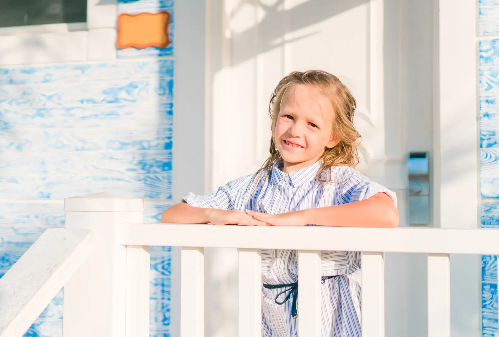Little adorable girl on a wooden bridge on their way to a white tropical beach and turquoise ocean.