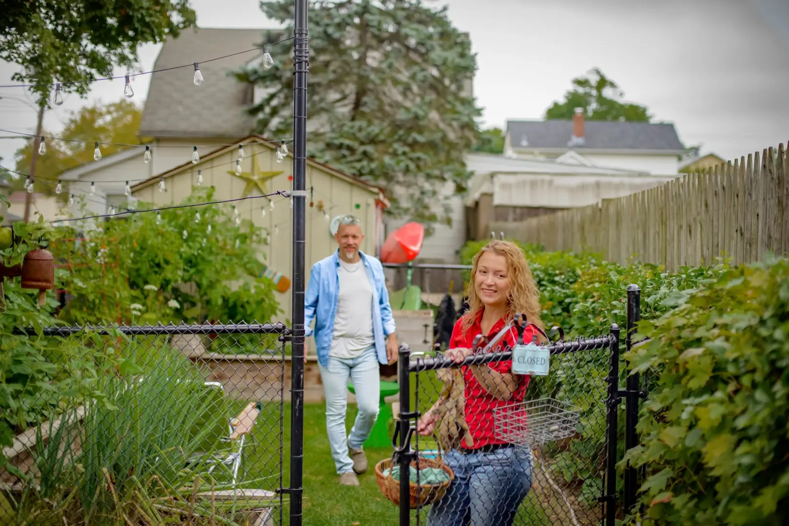 Portrait of mature gardening couple by garden gate.