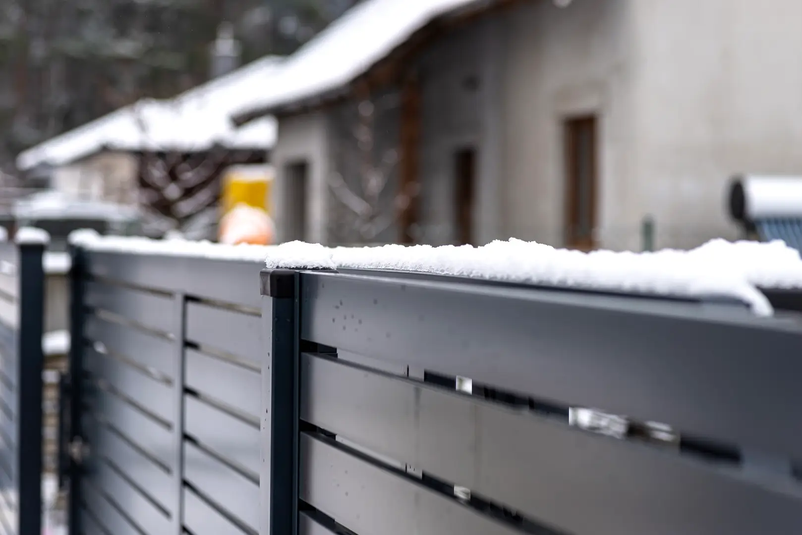 Steel fence in front of a home with snow on the ground.