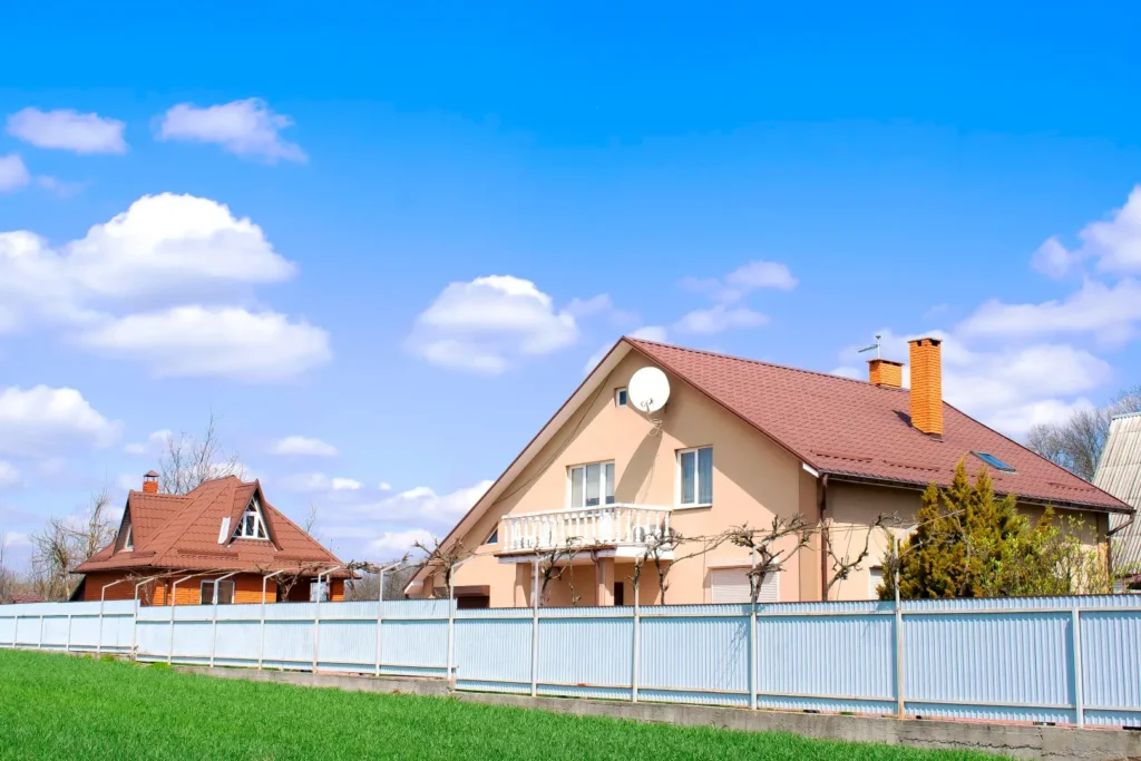 Vibrantly colored luxury homes with fresh green lawns, paved walkways, and sleek vinyl fences.