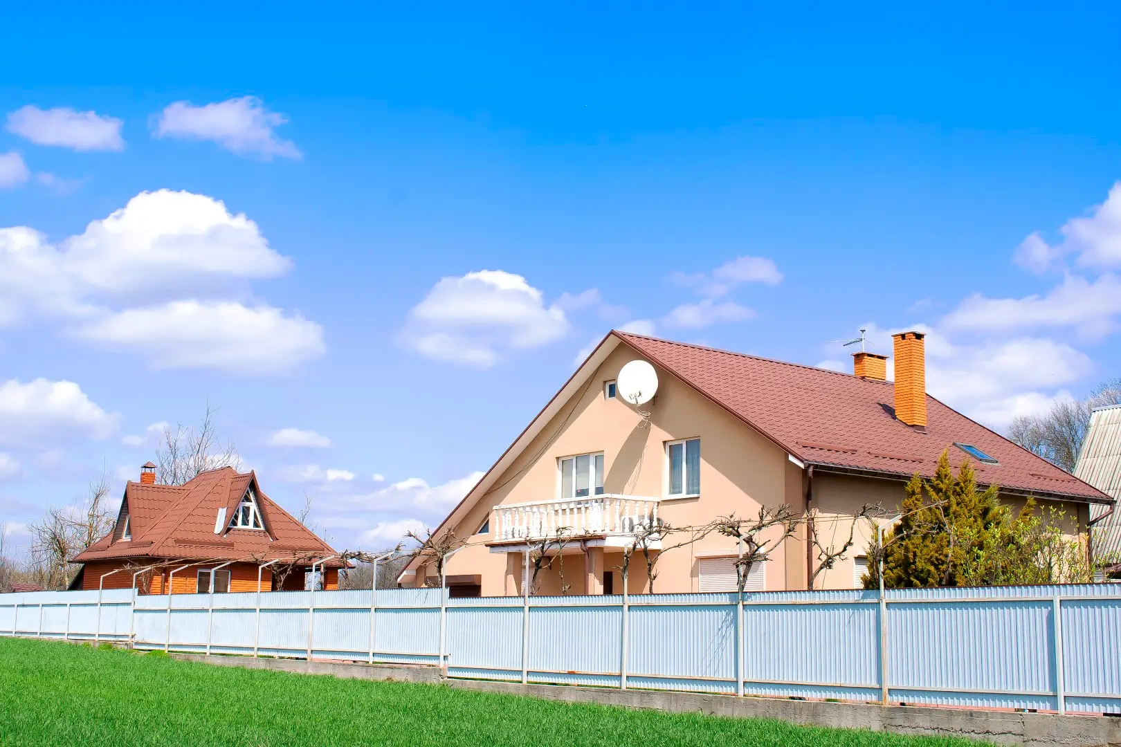 Vibrantly colored luxury homes with fresh green lawns, paved walkways, and sleek vinyl fences.