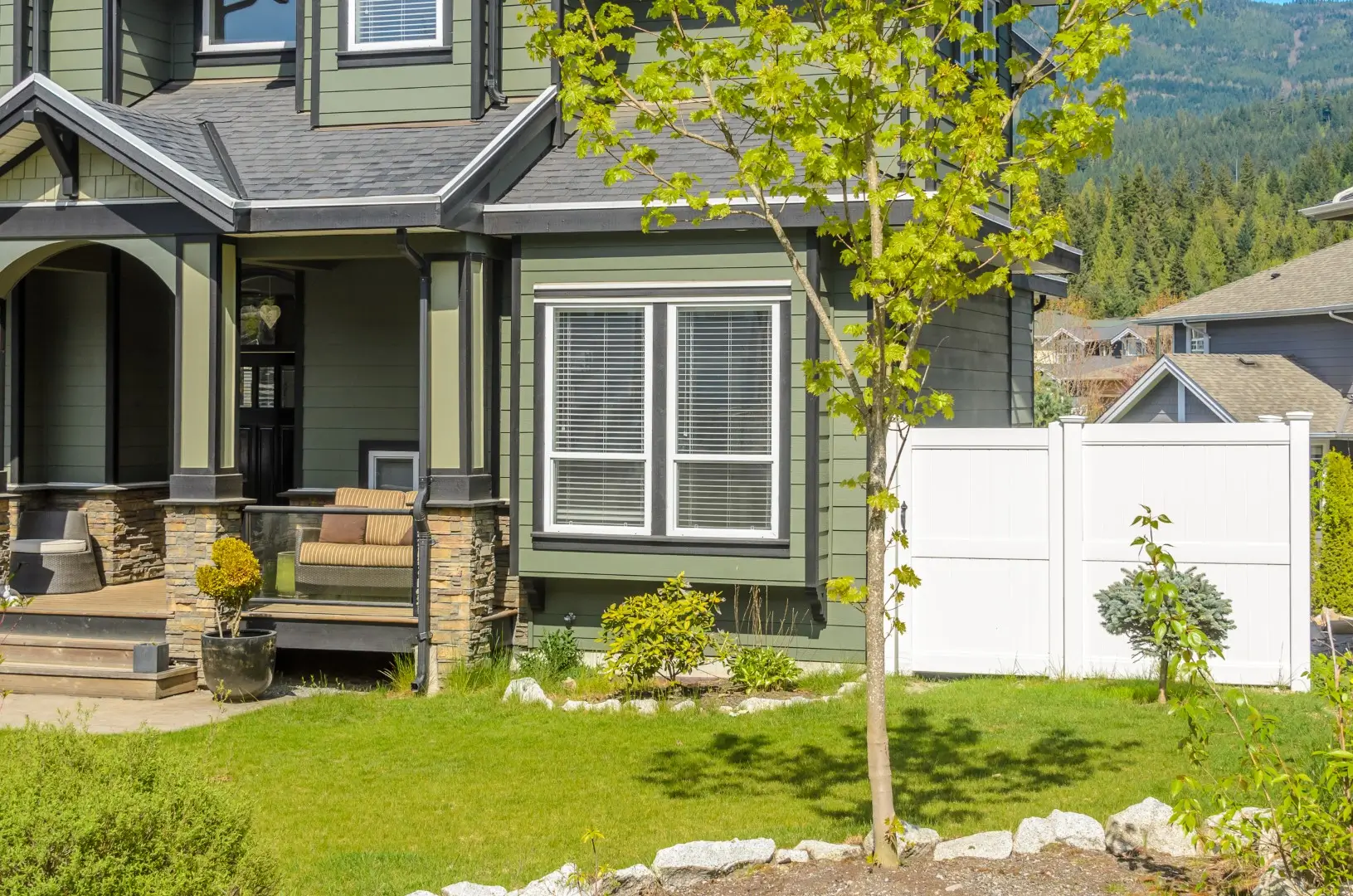 Vinyl fence around a home next to grass and trees.