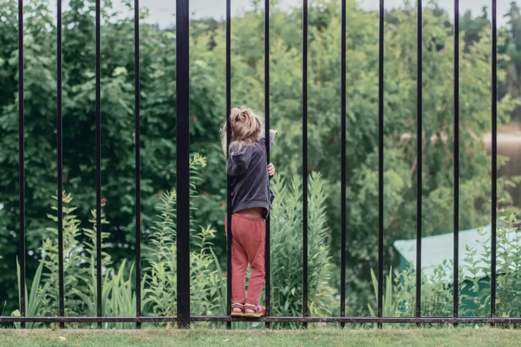 Young girl next to aluminum fence post.
