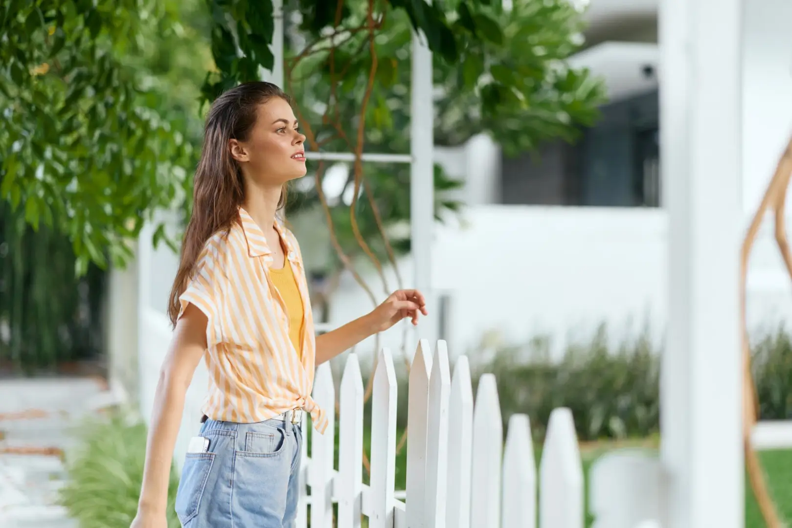 Young woman enjoying a sunny day outdoors enters a home through a vinyl gate.