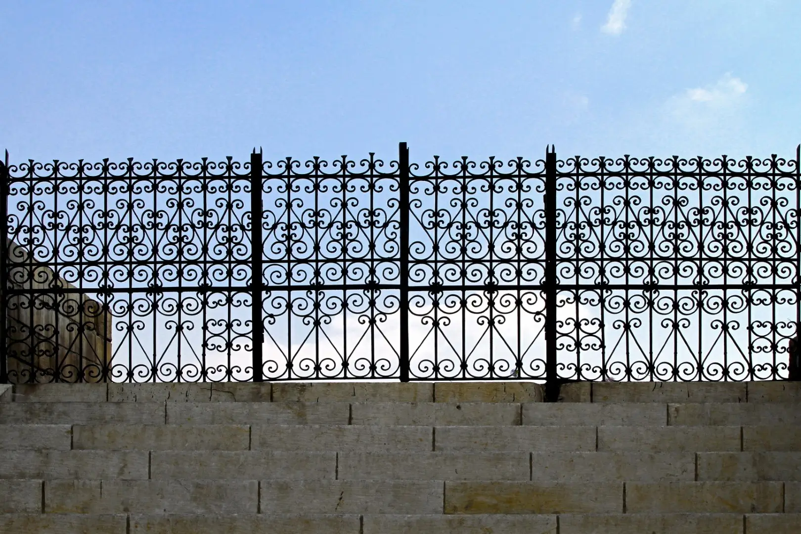 Iron Work Fence At Top Of Stairs set against a blue sky in the background.