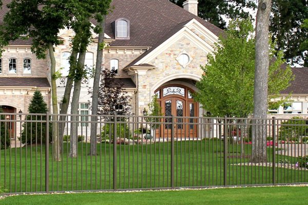 A white picket fence surrounding a charming house, creating a sense of security and privacy.