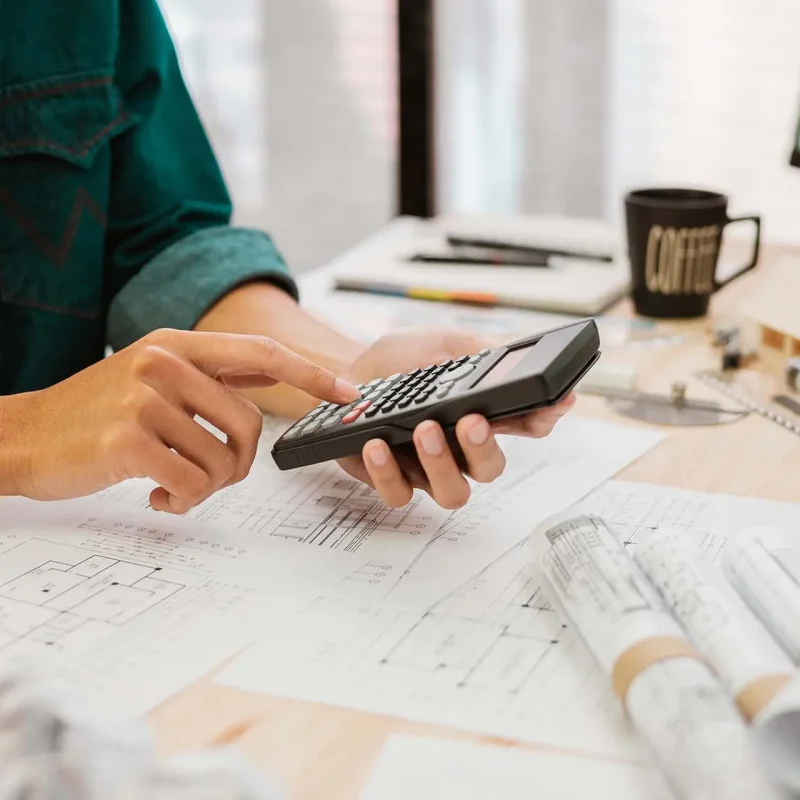 Close up Architect or Engineer pressing on calculator for calculating value estimating for safety with the drawing construction building.