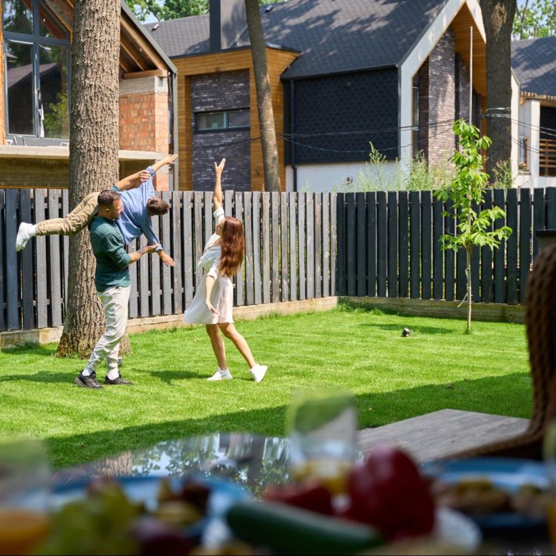 Family playing in a yard surrounded by fencing.