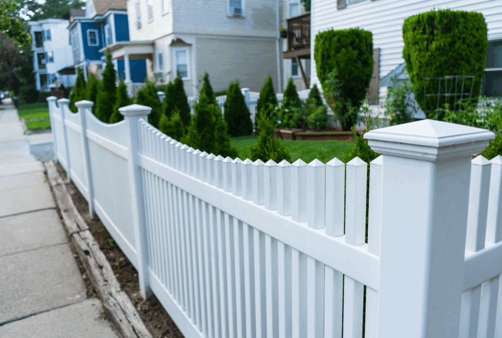 White vinyl picket fence with reinforced posts bordering a suburban front yard