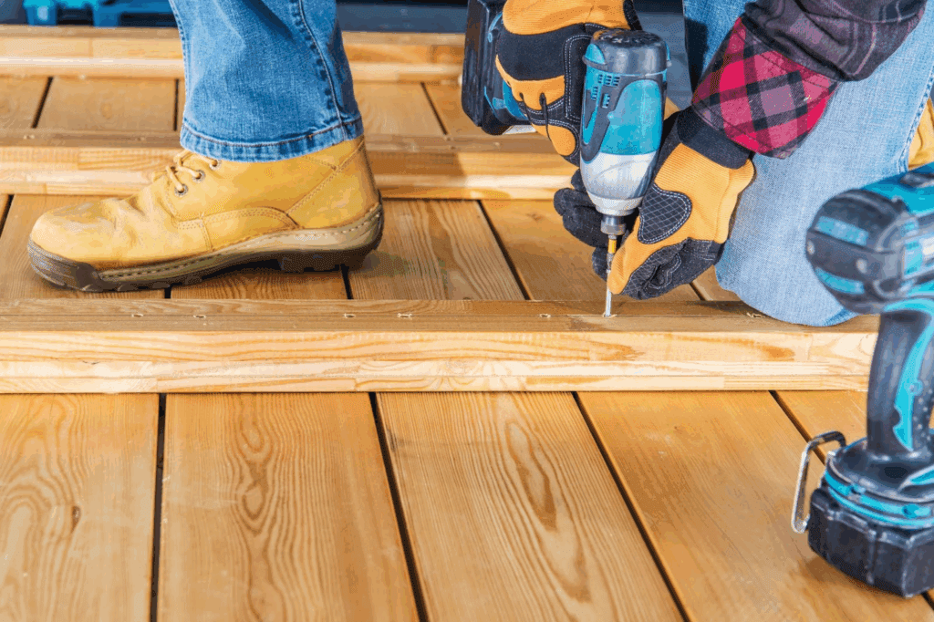 Close-up of a worker using a drill driver during deck construction
