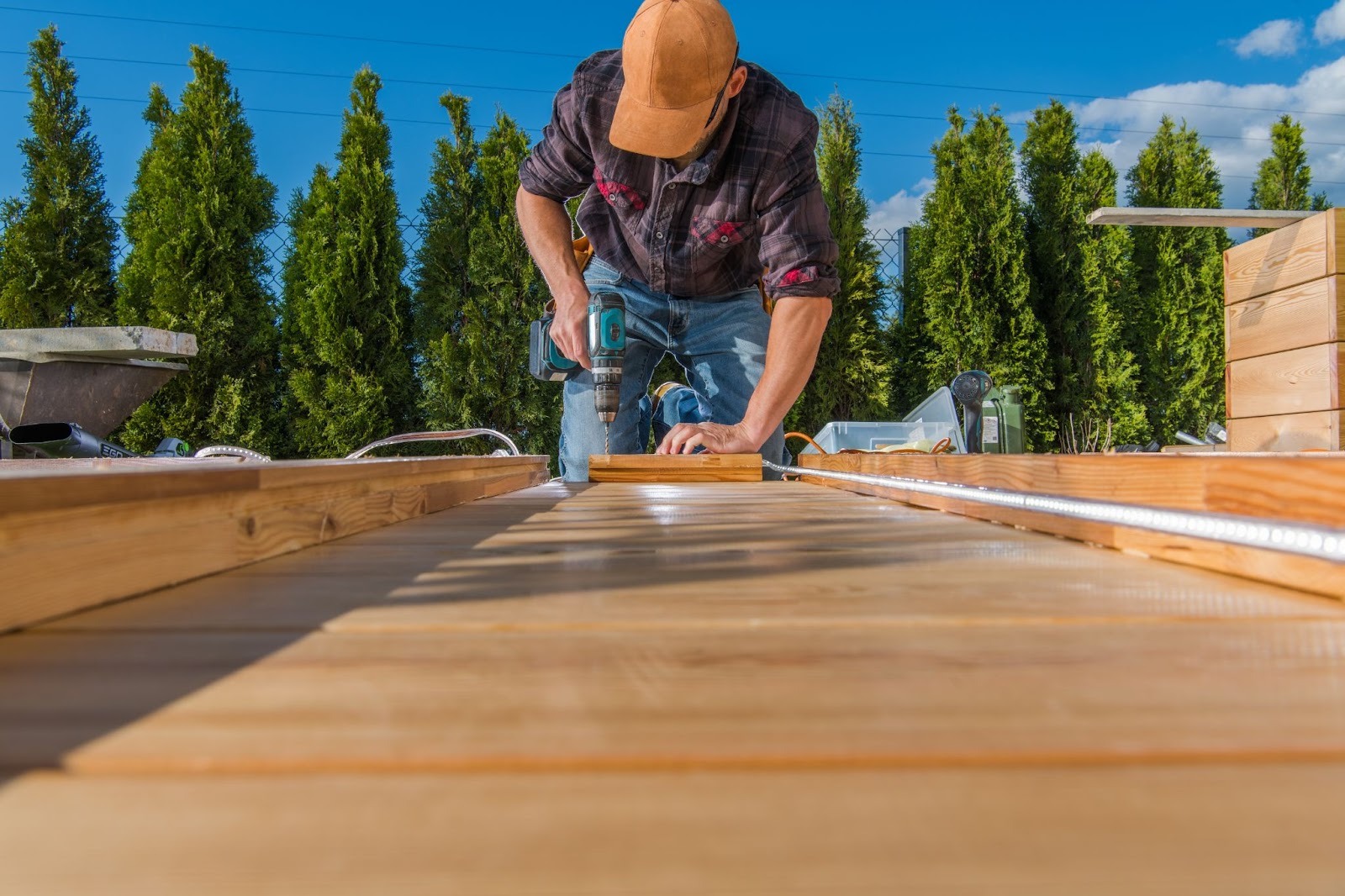 A deck builder drilling and assembling a wooden deck with precision and care