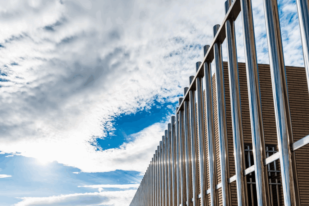 A long aluminum fence protects a brown building. 