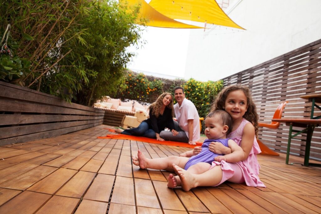 Parents look on as their children sit on their backyard deck.