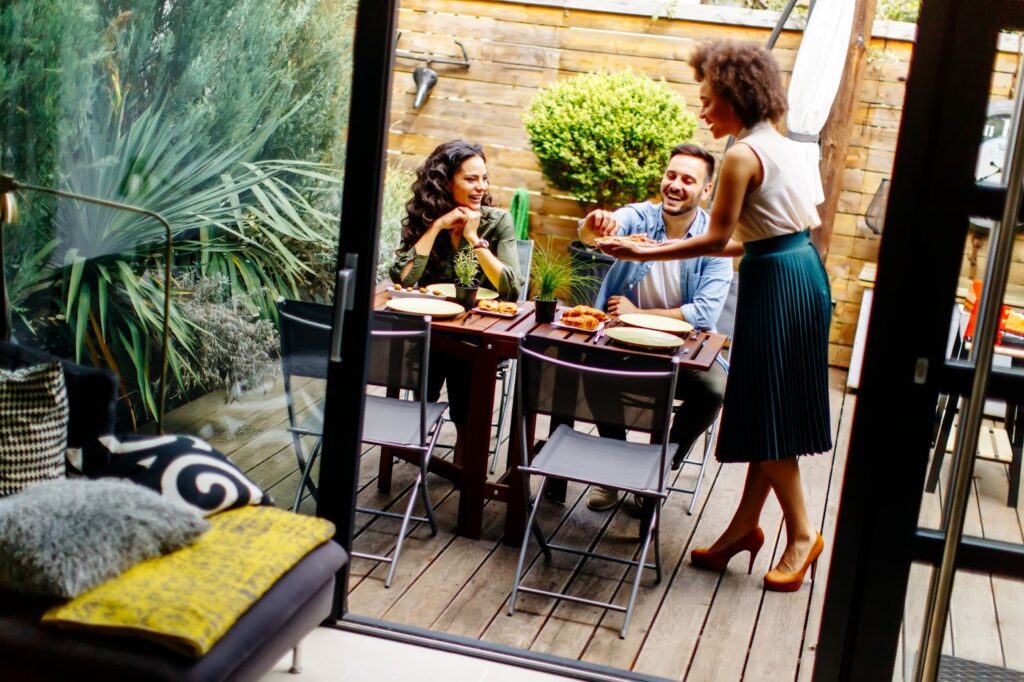 A view of three friends having lunch on their backyard deck.