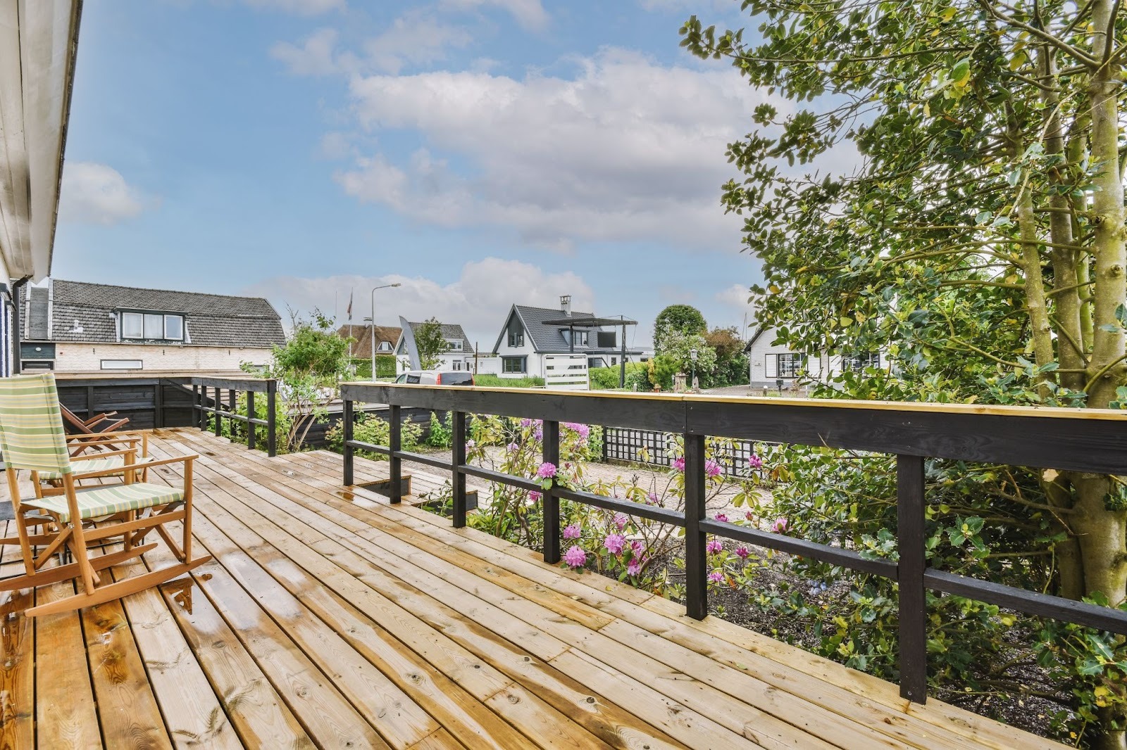 View from inside a spacious, luxurious balcony with a wooden deck and elegant black wood fences for safety and style.
