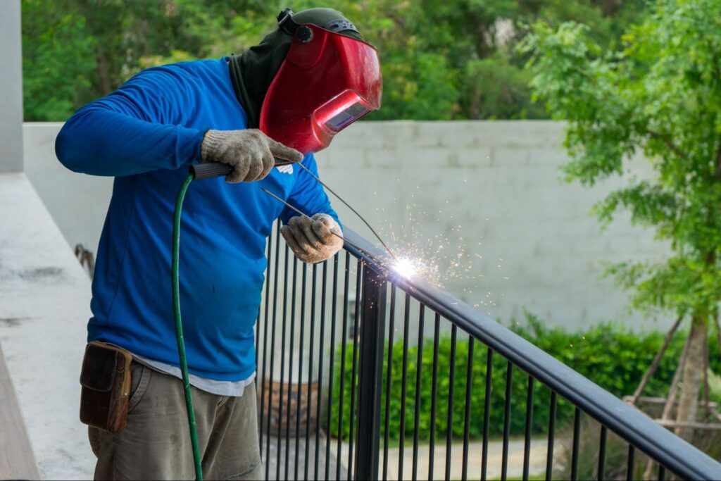 A welder is welding a steel fence.
