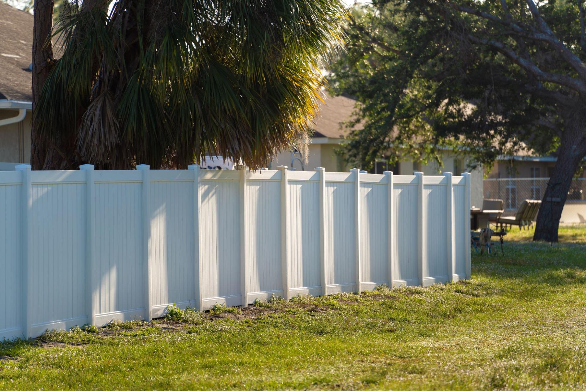 Vinyl fencing around a home next to trees.