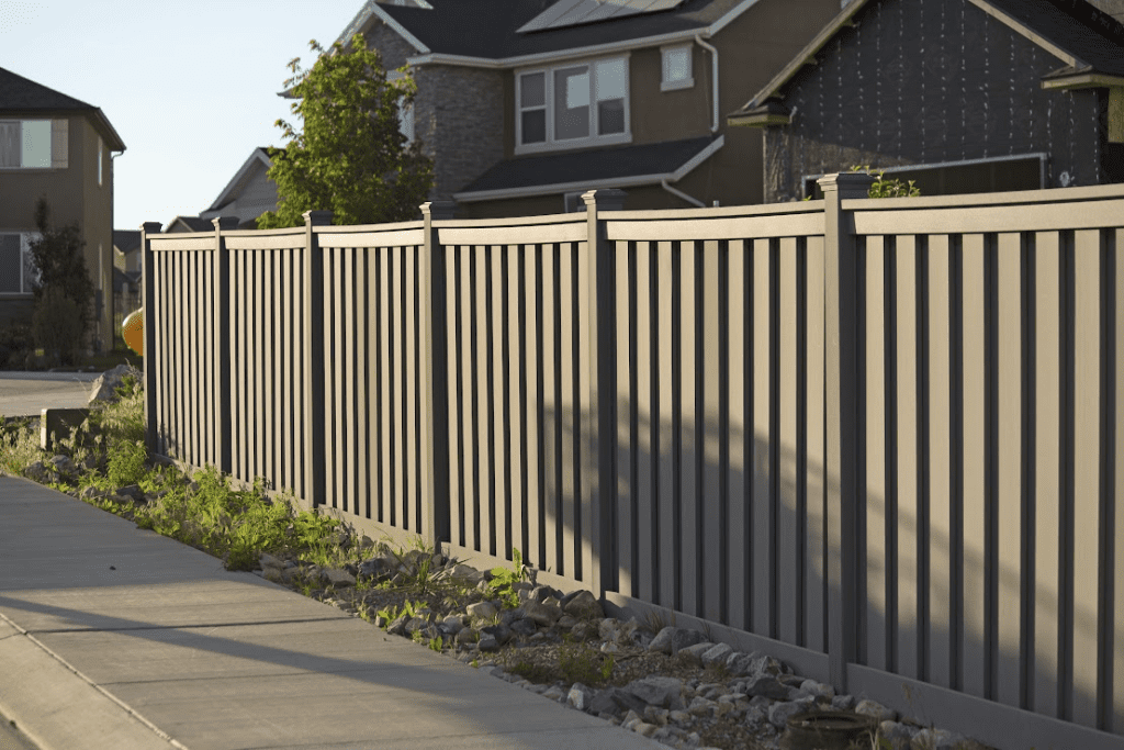 A grey vinyl fencing surrounding a home's property.