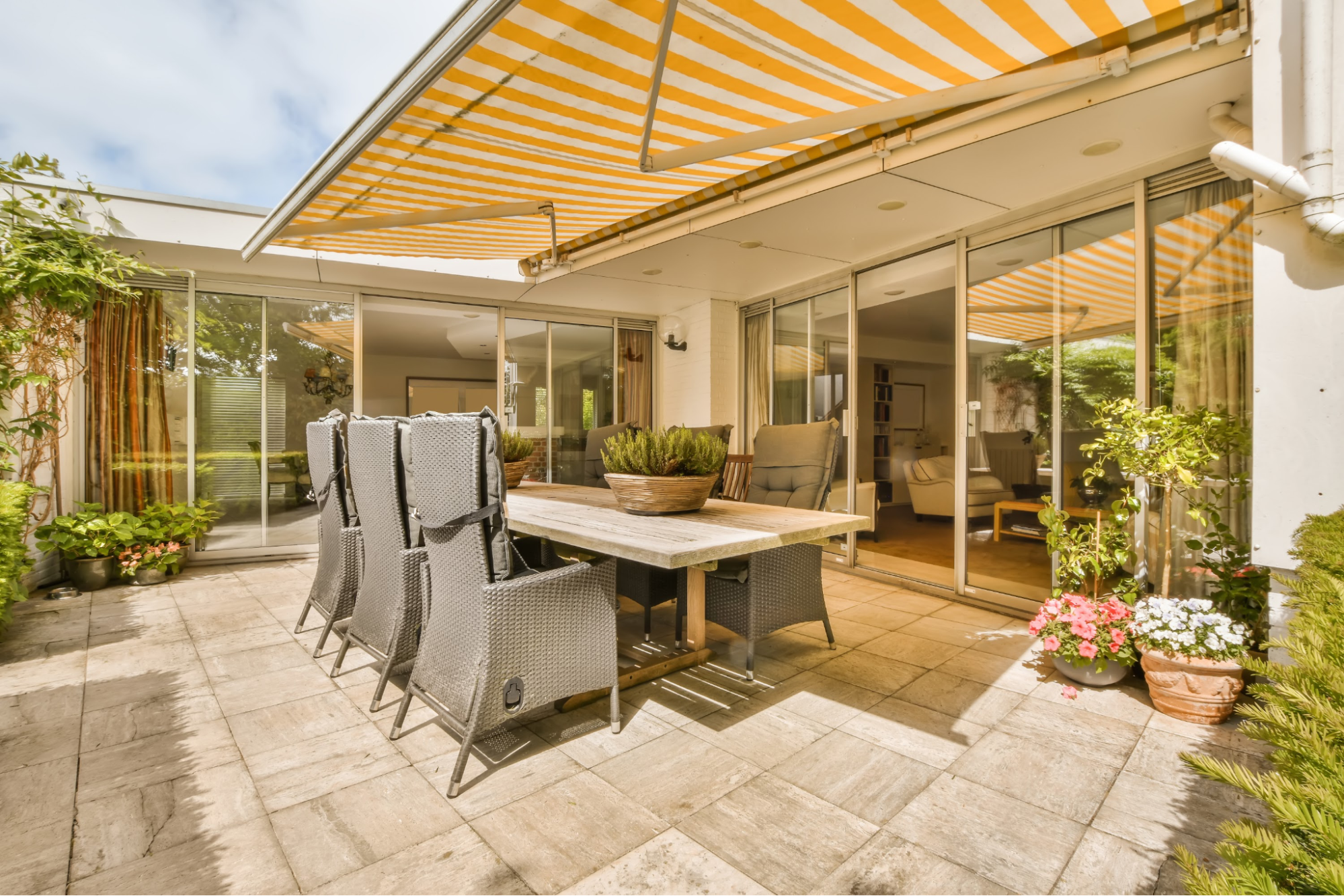 A modern patio covered with an orange striped awning.