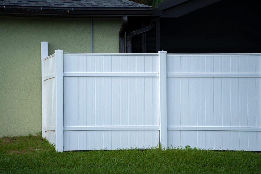 A white vinyl picket fence made with durable vinyl fence parts surrounds the property grounds.