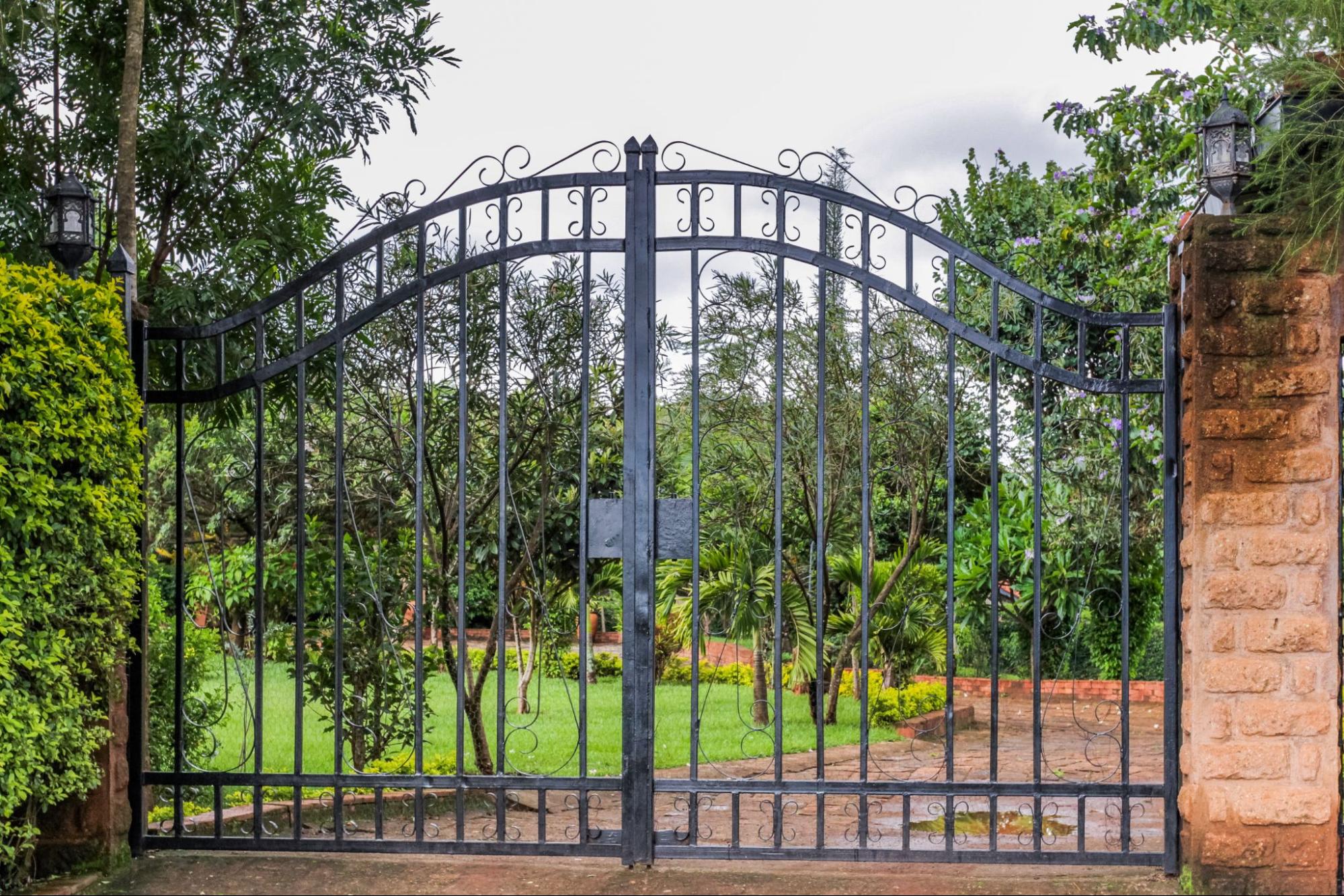 A black steel fencing gate at the entrance of a garden-fronted property.